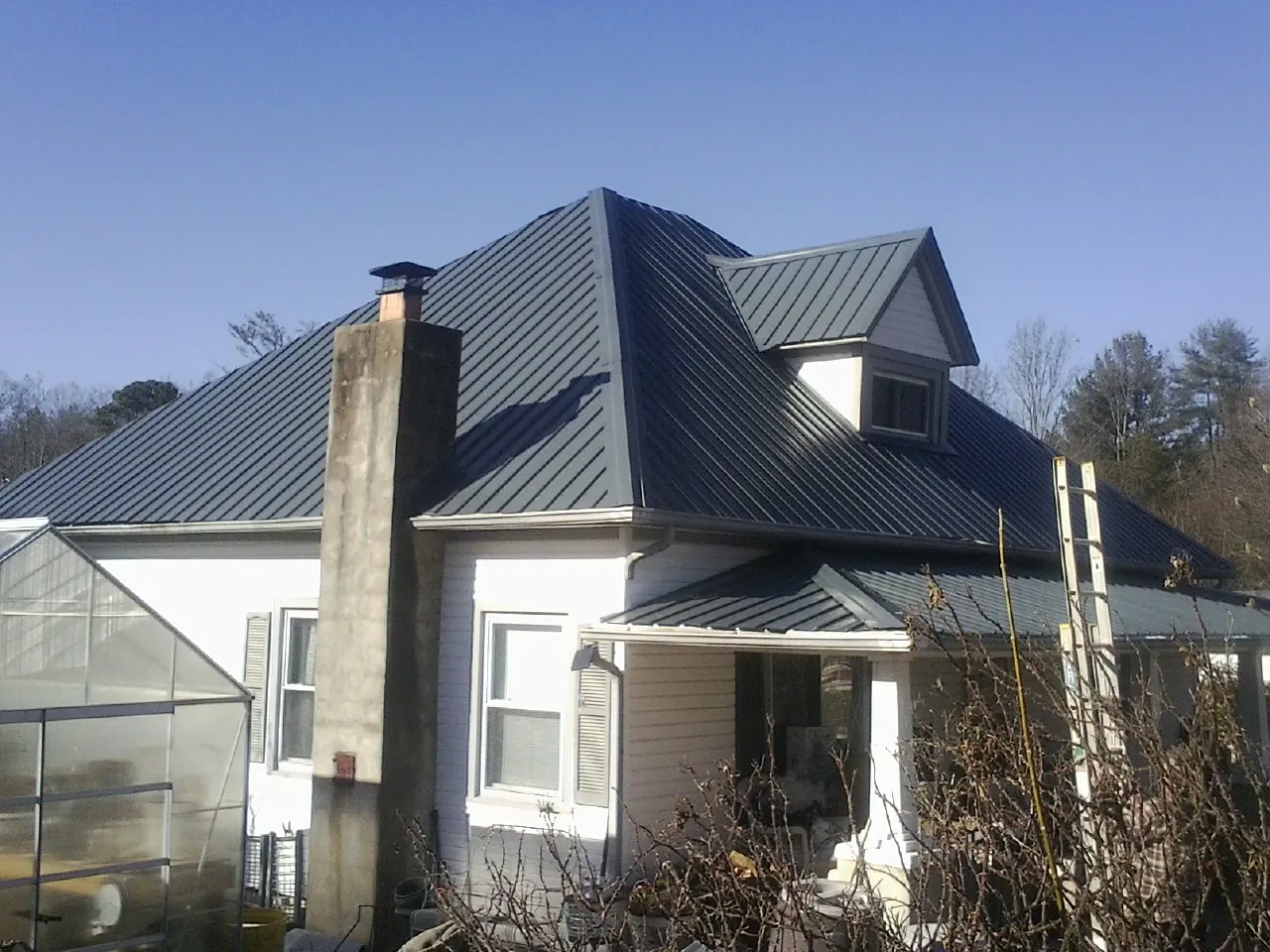 Dark blue standing seam metal roof on a white farmhouse with dormer — Slate & Tile Roof Repair by Roofing Brothers in New Bloomfield