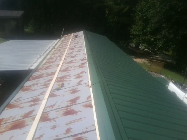 Old rusted panels beside newly installed green metal roofing — Wind Damage Roof Repair by Roofing Brothers in New Bloomfield