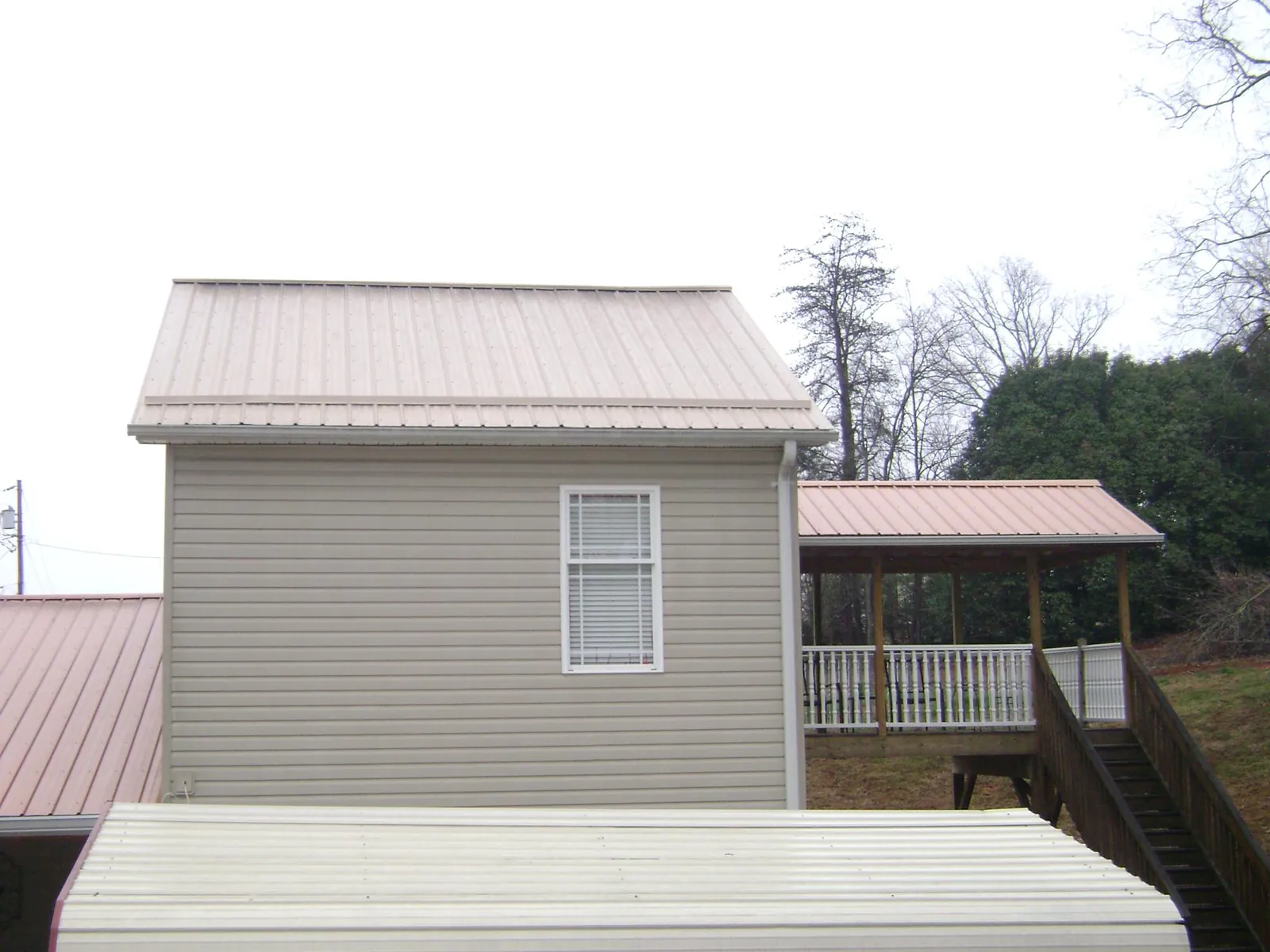 Tan metal roofs on a two story addition and attached porch, from a Roof Replacement job in New Bloomfield